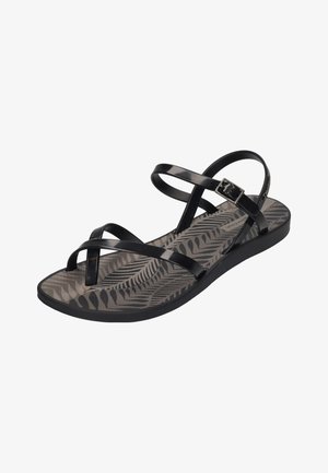 Black sandals with multiple glossy straps, featuring a textured grey insole with a fern pattern. Adjustable buckle closure on the side.