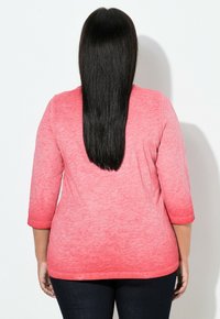 Korallysrosa, blød top i bomuldsblanding med trekvartlange ærmer og rundet kant, set bagfra. Tekstureret, let meleret finish.