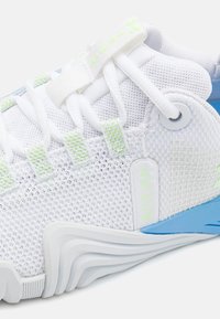 Pantofii sport albi cu un superior din plasă respirabilă, accente verzi deschise, talpă din cauciuc albastru și un detaliu logo proeminent.