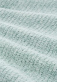 Tissu texturé vert clair avec une surface douce et duveteuse, présentant un motif côte à côte et de légentes vagues créant profondeur et dimension.