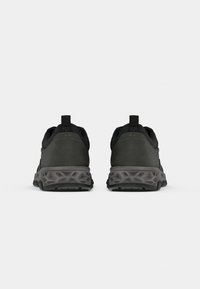 Schwarze und graue Sportschuhe mit einer strukturierten Gummisohle, einem gepolsterten Kragen und einer Zuglasche an der Rückseite für ein einfaches Anziehen.