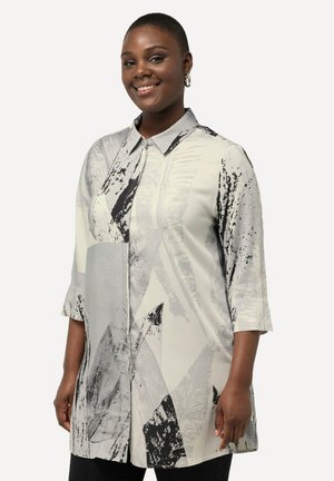 Chemise en gris clair avec des motifs abstraits noirs, design à boutons et manches trois-quarts. Elle présente un col structuré et un tissu lisse.