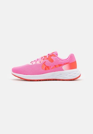 Pink net-løbesko med rød og orange Nike-swoosh, hvid polstret sål og rød ydersål, vist fra siden på en hvid baggrund.