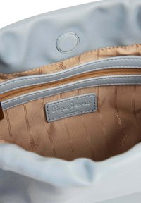 Svetlo modra usnjena torbica z bež satensko podlogo, z zlatimi zadrgami in oznako "Pepe Jeans London". Mehka, nabrana zasnova robov.