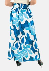 Falda maxi en un patrón floral azul y blanco, con una cinturilla fruncida y una tela fluida. El material parece ligero y transparente.