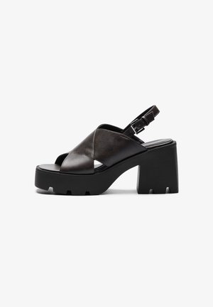 Sandale à plateforme en cuir noir à bout ouvert avec talon épais et bride de cheville ajustable avec boucle.