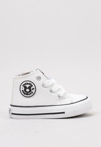 Zapatilla alta de lona blanca con detalles negros, logotipo redondo y cinco ojales para los cordones; suela de goma con agarre texturizado.