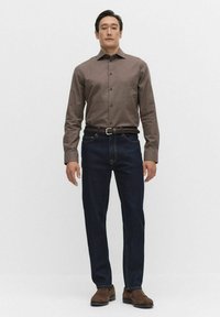Brun knapp-up skjorta, mörkblå jeans, flätad brun bälte, strukturerad tyg, och bruna skor. Enkel design, åtsittande stil.