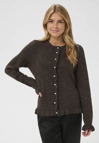 Cardigan marron tricoté avec des boutons en perle, un ourlet à volants et des manches longues. Présente une texture tachetée et un col rond.