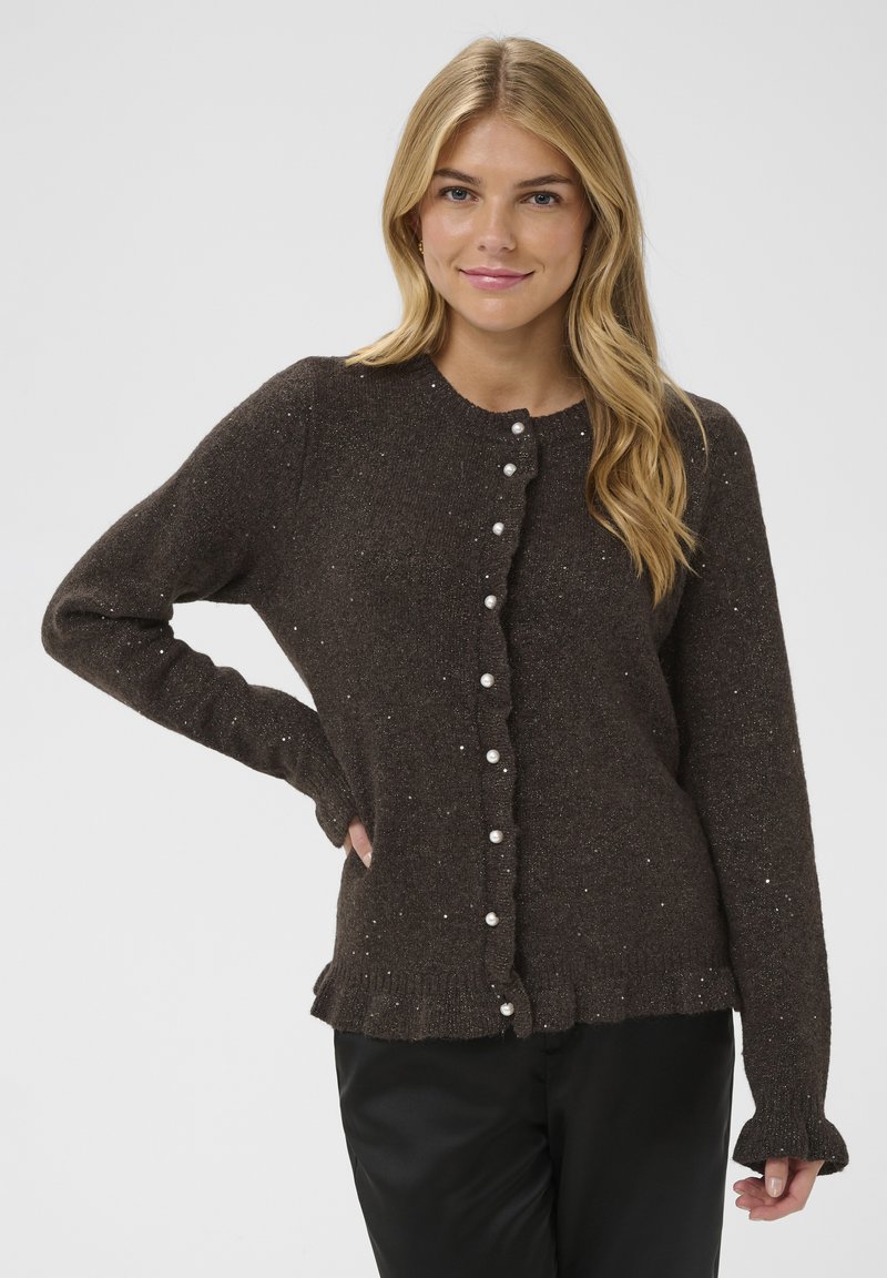 Cardigan marron tricoté avec des boutons en perle, un ourlet à volants et des manches longues. Présente une texture tachetée et un col rond.