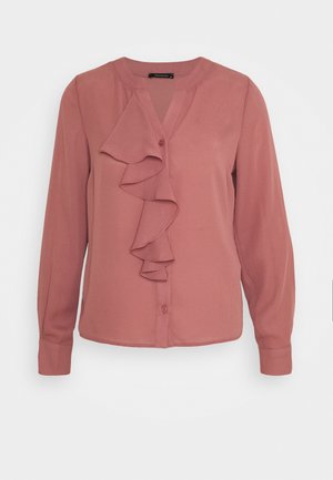 Langärmlige Bluse in Staubrosa mit Knopfleiste vorne und einem herabfallenden Rüschen-Detail entlang der Brust, kragenloser Ausschnitt.