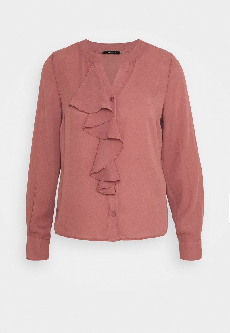 Blouse rose poussiéreux à manches longues avec fermeture à boutons sur le devant et un détail de volants en cascade le long de la poitrine, col sans col.