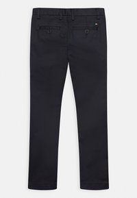 Svarta bomullsbukser med rak benstil, två bakfickor med knappar och bälteshällor. Slät textur med en ren finish.