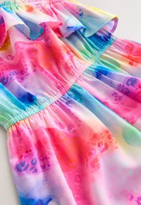 Rochie colorată și ușoară, cu gât îmbrăcat în volane și talie încrețită. Materialul prezintă un amestec de modele abstracte în roz, albastru și violet.