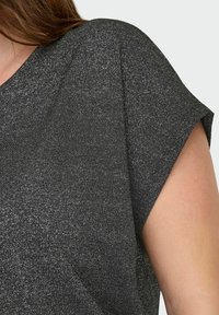 Haut noir à manches courtes en tissu texturé avec un subtil éclat. Présente une coupe décontractée et des manches larges, mettant en avant le confort et la liberté de mouvement.