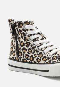 Sneakers wysokie w panterkę, wykonane z płótna z białymi sznurówkami, wyposażone w boczny zamek błyskawiczny, czarną gumową podeszwę i kontrastowe paski.