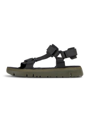 Black sandal featuring adjustable straps, a textured sole, and olive green midsole. The design is open-toed with a sporty aesthetic.