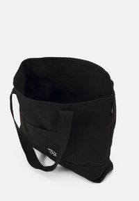 Black canvas tote bag with a spacious interior, sturdy straps, and a small external pocket. Features a simple, clean design.