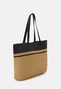 Sac fourre-tout texturé en paille tissée beige avec une bande de motif noir et des poignées, présentant une forme rectangulaire structurée.