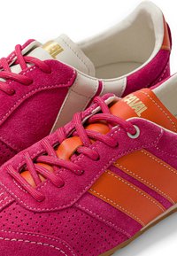 Paire de baskets en daim rose avec des bandes en cuir orange, des lacets roses et des coutures blanches sur fond blanc.