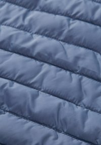 Vystužená látka v jemnej tmavomodrej farbe s prešívaním, s hladkým povrchom a jemným leskom.