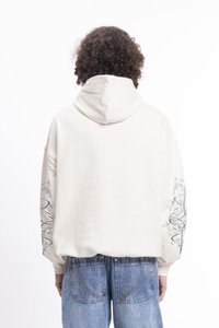 Kreemi värvi ülisuur kapuutsiga pusa koos tekstuuriefektiga, mille varrukatel on hallid abstraktsed mustrid. Sobib siniste denimplaaditud lühikeste pükstega.