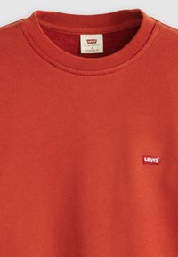 Piros pamut pulóver kerek nyakkal, bal mellen egy kis fehér és piros Levi's logóval. Normál fazon.