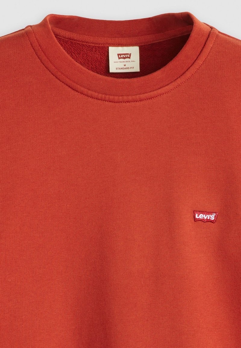 Czerwony bawełnowy sweter z okrągłym dekoltem, ozdobiony małą białą i czerwoną naszywką z logo Levi’s po lewej stronie klatki piersiowej. Standardowy krój.