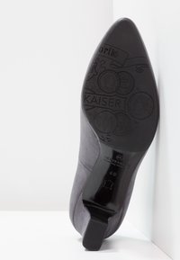 Chaussure à talons hauts en suède gris avec un bout pointu et une semelle noire lisse, dotée de détails en relief et d'une marque au talon et à la semelle intérieure.