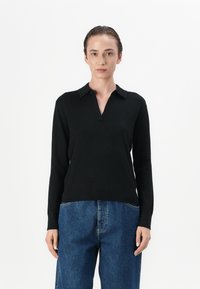 Zwarte lange mouwen pullover met een V-hals en kraag. Gemaakt van een zachte stof, met een aansluitend lichaam en iets losse mouwen.
