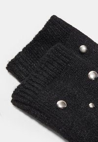 Guanti senza dita lavorati a maglia neri con texture a coste, con accenti in metallo argentato disposti in una linea su un lato.