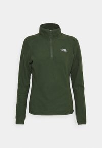 Pullover in pile verde scuro con colletto a mezza zip, maniche lunghe e un piccolo logo bianco sul lato sinistro del petto. Texture liscia.
