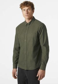 Camisa de manga larga de hombre en tela verde oscuro, con cuello, dos bolsillos en el pecho y un sutil acabado texturizado.