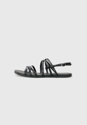 Schwarze Ledersandalen mit mehreren schlanken Riemen, einer flachen Sohle und einem verstellbaren Knöchelriemen mit einem runden Schnallen-Detail.