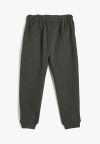 Grå sweatpants lavet af tekstureret stof, med elastisk talje og indsnævrede manchetter ved anklerne. Ingen lommer eller yderligere detaljer.