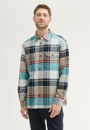 Karierter Hemd in Türkis-, Beige- und Marinefarben. Klassischer Kragen, Knopfverschluss vorne und zwei Brusttaschen mit Klappen. Aus Flanell gefertigt.