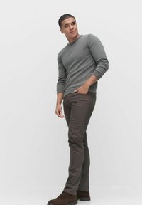 Grå långärmad skjorta, bruna slim-fit byxor och mörkbruna skor. Slät tygkvalitet med figursydd design, stående pose mot en vit bakgrund.