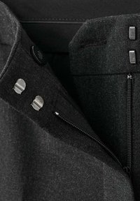 Veste en mélange de laine noire avec une texture lisse, dotée de quincaillerie argentée, d'une fermeture à boutons et d'une poche zippée.