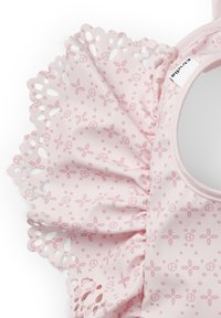 Rosa tyg med blommönster och utskurna scalloped kanter, med en mjuk textur och rund halsringning. Lapps synlig.