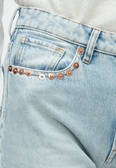 Φωτεινό γαλάζιο τζιν με τσέπη διακοσμημένη με τρουκ χαλκού κατά μήκος της ραφής, με ξεθωριασμένη υφή και κλασικό σχέδιο.
