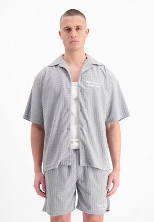 Lichtgrijze, kortekleding met korte mouwen en bijpassende shorts met gestructureerde, geweven patronen; het shirt heeft een knoopsluiting en geborduurd logo detail.