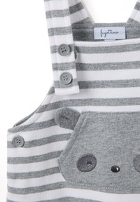 Peto a rayas gris y blanco con dos botones grises, que presenta un bolsillo con la cara de un oso gris y detalles bordados. Tejido de algodón suave.