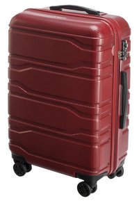 Valise rigide rouge avec finition texturée, lignes d'accentuation, double fermeture éclair et quatre roues pivotantes pour une mobilité facile. Design compact et robuste.