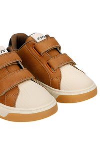Paire de baskets marron et beige pour tout-petit avec des bandes Velcro et des semelles en caoutchouc sur fond blanc.