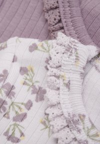 Två tyggprov: en lavendelfärgad ribbad strik och en vit med lila blommönster, som har en texturerad volangkant i mjuk lavendel.