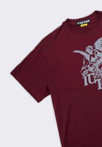 T-shirt corto a maniche corte di colore maroon con grafica bianca di un angelo e il testo in grassetto "IUTER" sul davanti e etichetta di taglia media all'interno del colletto.