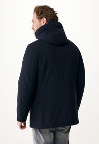 Veste à capuche bleu marine en tissu lisse avec une coupe droite, dotée d'une couture au dos et d'une petite étiquette de marque sur l'épaule.