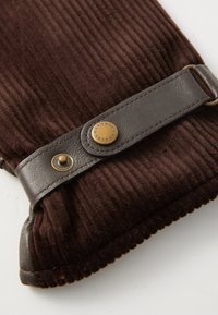 Bruine corduroy handschoen met een bruine leren band en details van een messing knoop. De handschoen heeft een textuurafwerking en een gekartelde rand.