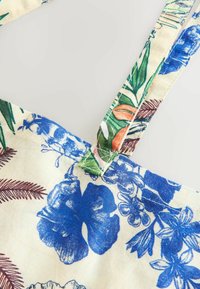 Blomstret stof med blå hibiscus og grønne blade. Letvægts med justerbare stropper og afsluttede kanter. Struktureret bomuldsblanding.