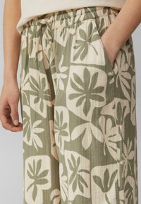Lichte, gemusterde broek in groen en crème, met grote bladmotieven, een elastische tailleband en zijzakken voor functionaliteit.